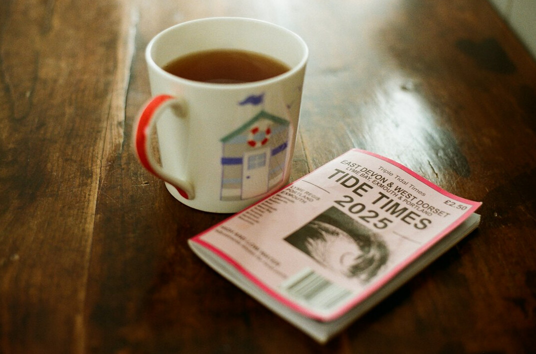 Folded newspaper on a table with a cup of tea